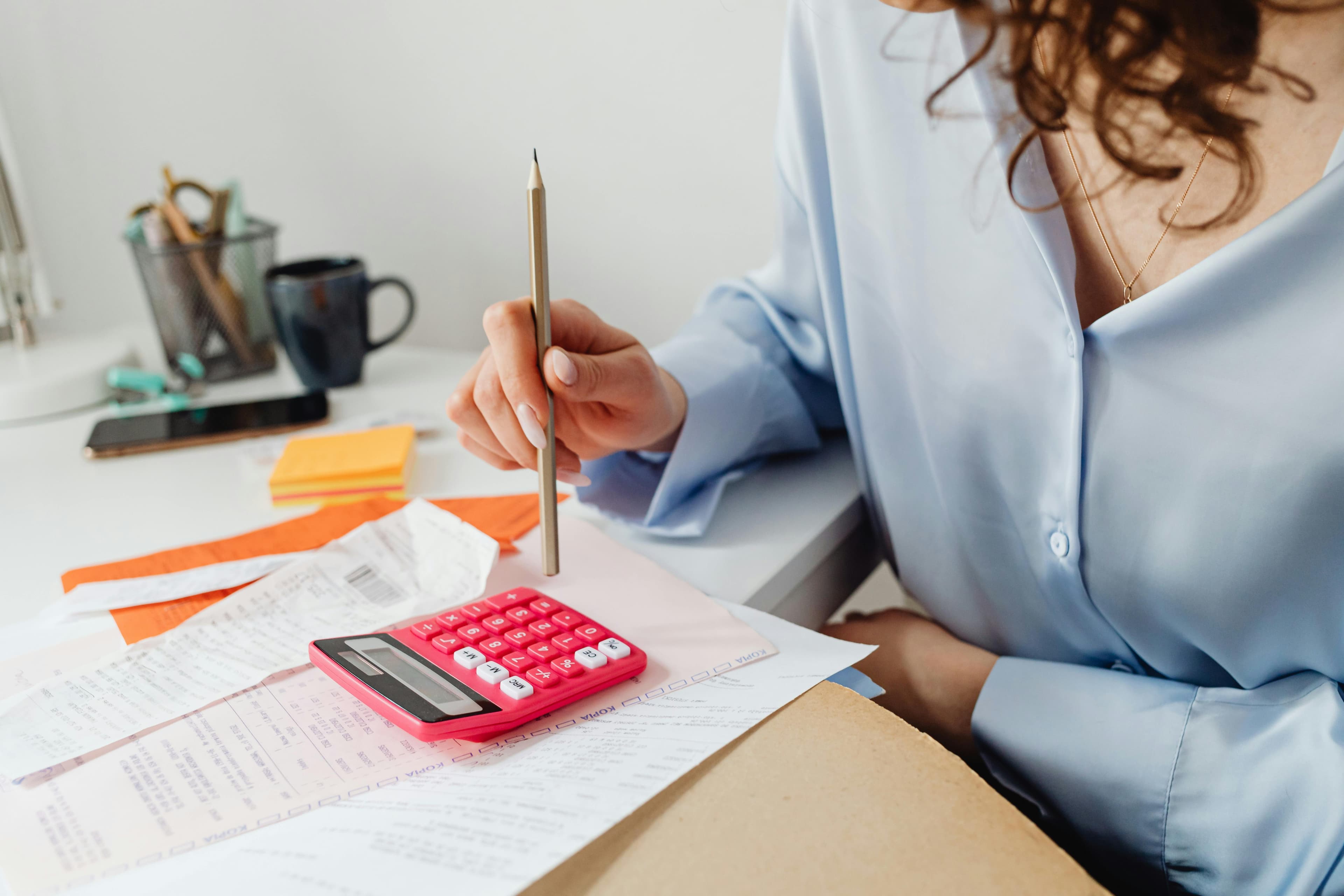 A bookkeeper sits at a table.  His their rests on a notebook. They study the charts and spreadsheets.